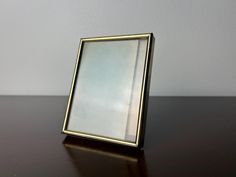 a mirror sitting on top of a wooden table next to a white wall in the background