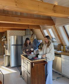 two women are preparing food in the kitchen together, while another woman stands at the counter