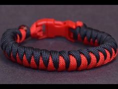 an orange and black bracelet on a gray surface with a red clasp in the middle