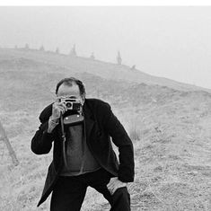 a man taking a photo with his camera on the side of a hill in black and white