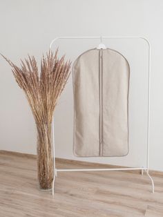 an ironing board and dry grass in a vase on the floor next to it