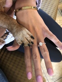 a woman's hand with two rings on it and a dog paw in the middle