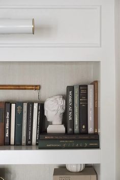 some books are sitting on top of a shelf in a room with white walls and gold trim