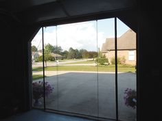 an open garage door with some flowers in the window sill and a house behind it