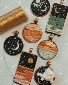 five embroidered pendants are sitting on a table with gold sequins and thread