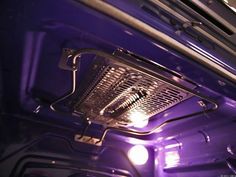 the interior of a car with its lights on and it's hood up in purple light