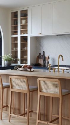 the kitchen is clean and ready to be used for cooking or eating, with two bar stools in front of the island