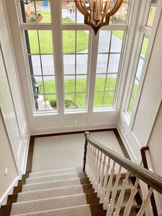 the stairs lead up to two large windows and a chandelier hanging from the ceiling