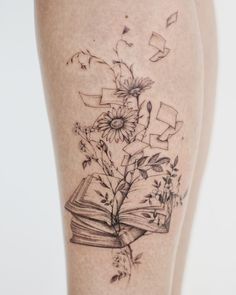 a woman's leg with a book and flowers on it