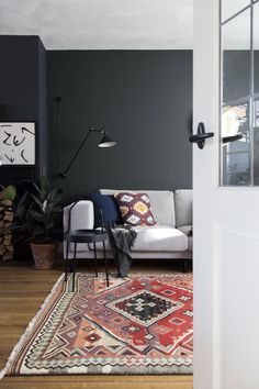 an image of a living room with dark green walls and rugs on the floor