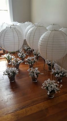 white paper lanterns with flowers in them on a wooden floor