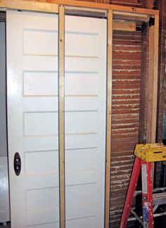 a white door is being installed in a room with brick walls and wood flooring