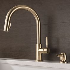 a gold faucet on the side of a white sink next to a brown wall