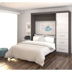 a white bed sitting next to a wooden floor in a room with hardwood floors and walls