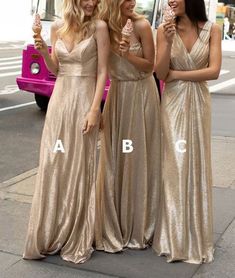 three beautiful women standing next to each other in gold dresses holding ice cream cones and looking at the camera