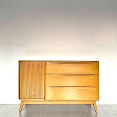 a wooden dresser sitting on top of a hard wood floor next to a white wall