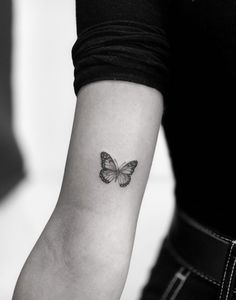 a black and white photo of a butterfly tattoo on the left inner arm, showing its wings