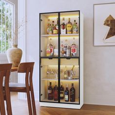 an open cabinet filled with liquor bottles on top of a wooden floor next to a dining room table