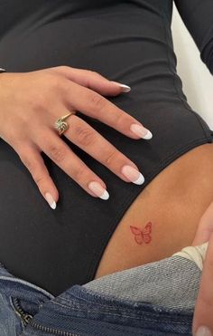 a pregnant woman's belly with a butterfly tattoo on her left side, while the lower half of her stomach is visible