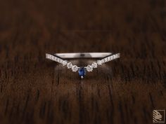 a diamond and blue sapphire ring on a wooden surface