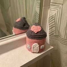 two knitted hats sitting on top of a counter in front of a bathroom mirror