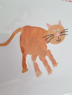 a paper cut out of a cat on a white surface with red writing underneath it