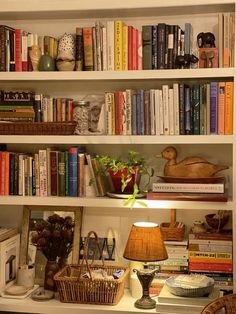 a bookshelf filled with lots of books next to a lamp and other items