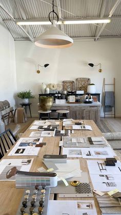 a long table with many pieces of paper on it in a room that has chairs and tables