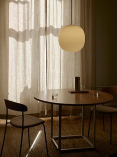 a table and two chairs in front of a window with curtains on the windowsill