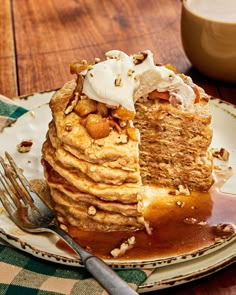 a stack of pancakes on a plate with syrup and whipped cream next to a fork