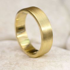 a gold wedding ring sitting on top of a white surface