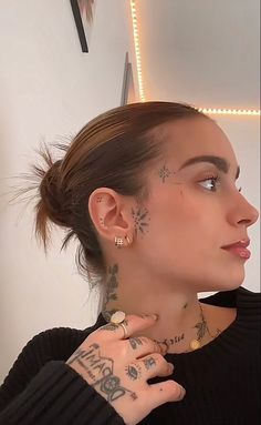 a woman with tattoos and piercings on her neck is looking at the camera while wearing a black sweater