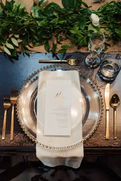 a place setting with silverware and greenery