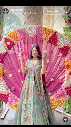 a woman standing in front of a pink and yellow flowered fan with her hands up