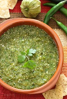 a bowl filled with green salsa next to tortilla chips