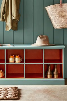 a blue bench with red cubbys and hats hanging on the wall next to it