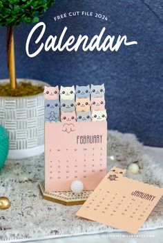 a calendar sitting on top of a table next to a potted plant and a small tree