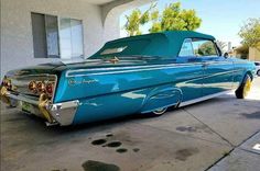 an old blue car parked in front of a house