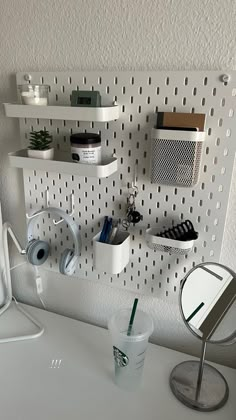 a white desk topped with a computer monitor next to a cup