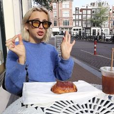 a woman sitting at a table with a pastry in front of her and a drink