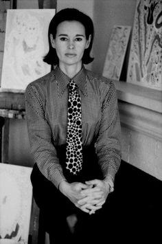 black and white photograph of a woman sitting in front of paintings