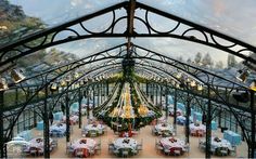 the inside of a restaurant with tables and chairs covered in christmas decorations under a glass roof