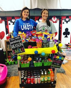 two women standing behind a table filled with drinks and snacks for an event or party