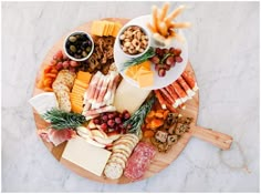 an assortment of cheeses, meats and crackers on a wooden platter