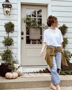 a woman is walking out of a house with her hand in her pocket and looking at the door