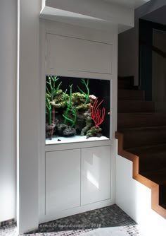 a fish tank sitting on top of a white cabinet next to a stair case in a room