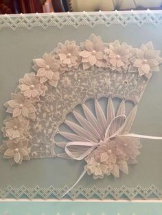 an intricately designed card with flowers on it's side and ribbon around the edge