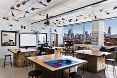 an empty classroom with desks and chairs in front of large windows overlooking the city