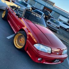 a red car with gold rims parked in a parking lot