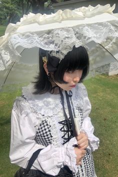 a woman with black hair wearing a white dress and holding an umbrella over her head